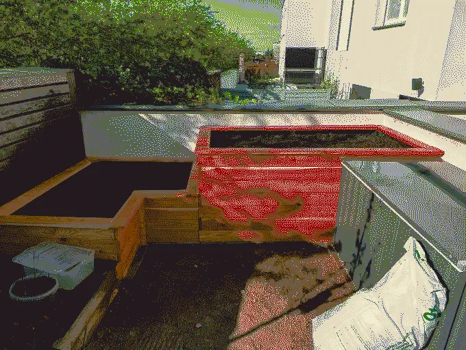 
              An L-shaped raised bed planter made of wood on a sunny day
            